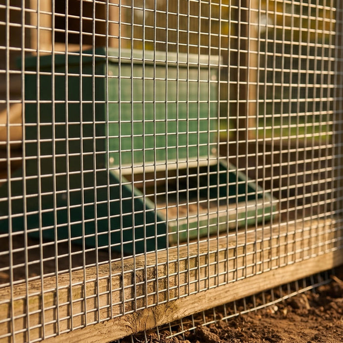 Close-up of small-gauge wire mesh on a chicken run with feeder inside